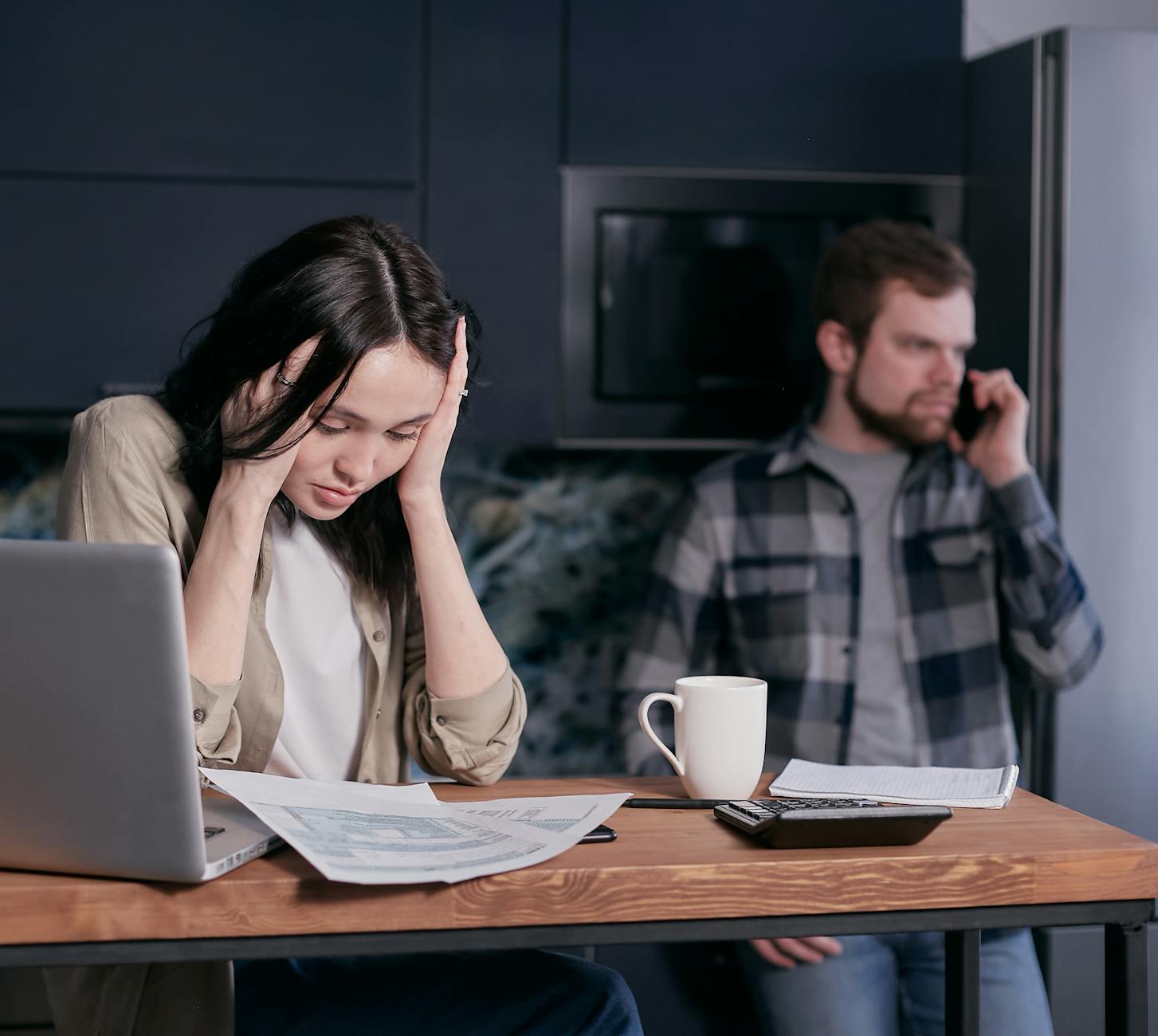 a stressed woman looking at the papers on a wooden desk